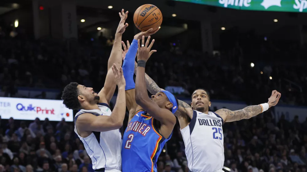 Oklahoma City Thunder guard Shai Gilgeous-Alexander (2) looks to shoot between Dallas Mavericks guard Quentin Grimes, left, and forward P.J. Washington (25) during the second half of an NBA basketball game Thursday, Jan. 23, 2025, in Oklahoma City. (AP Photo/Nate Billings)