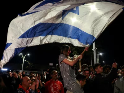FILE PHOTO: A woman waves an Israeli flag, as people gather on the day of the arrival of Romi Gonen, Doron Steinbrecher and Emily Damari, three former female hostages who have been held in Gaza since the deadly October 7 2023 attack, following their release as part of a ceasefire deal in Gaza between Hamas and Israel, at Sheba Medical Center in Ramat Gan, Israel January 19, 2025. REUTERS/Ronen Zvulun/File Photo