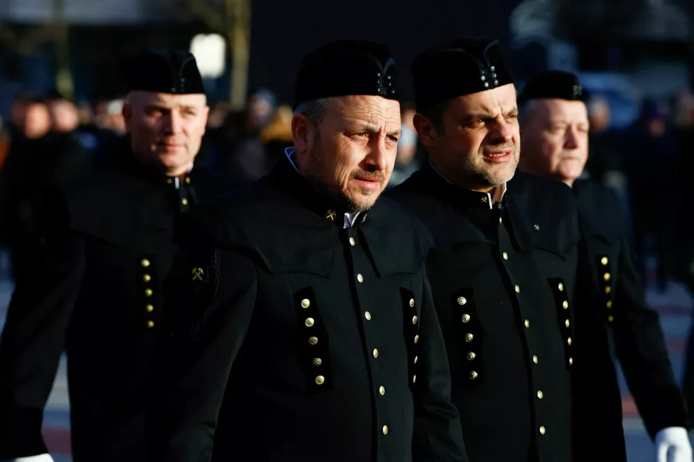 Miners in official uniforms walk near the statue of a miner, as they mourn for the miners who died in the Velenje coal mine, in Velenje, Slovenia January 24, 2025. REUTERS/Borut Zivulovic