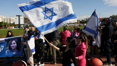 A woman waves an Israeli flag as people wait for the expected arrival of released Israeli hostages, who have been held in Gaza since the deadly October 7, 2023 attack by Hamas, as part of a prisoner-hostage exchange deal between Israel and Hamas, in Petah Tikva, Israel, January 25, 2025. REUTERS/Ronen Zvulun