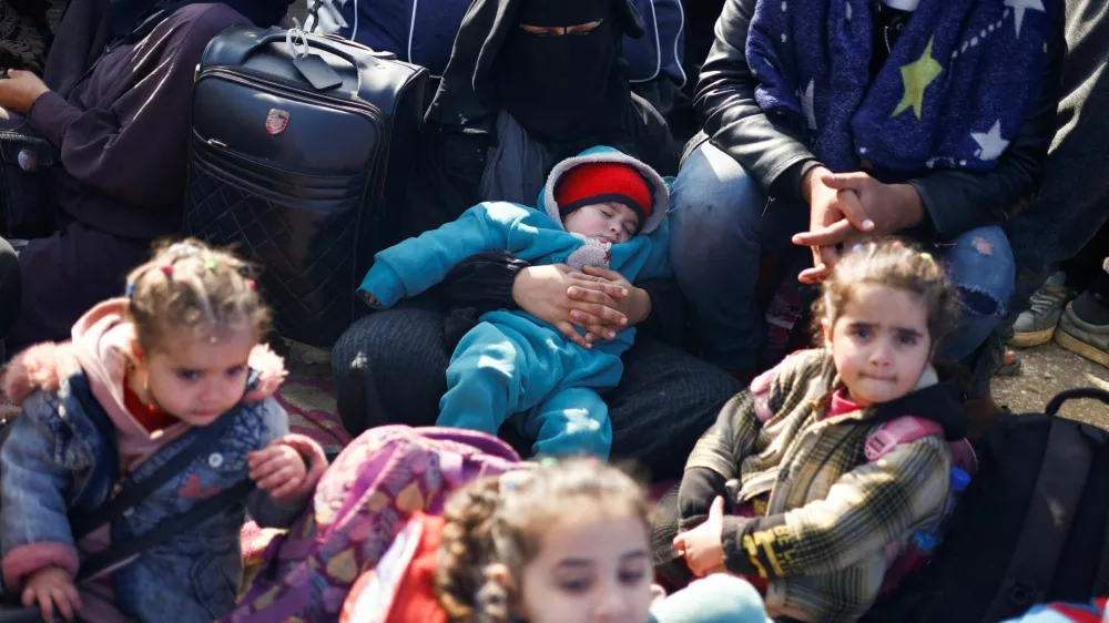 A woman holds a baby while sleeping as Palestinians wait to be allowed to return to their homes in northern Gaza after they were displaced to the south at Israel's order during the war, amid a ceasefire between Israel and Hamas, in the central Gaza Strip, January 26, 2025. REUTERS/Mohammed Salem