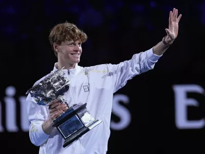 Jannik Sinner of Italy waves as he carries the Norman Brookes Challenge Cup after defeating Alexander Zverev of Germany in the men's singles final at the Australian Open tennis championship in Melbourne, Australia, Sunday, Jan. 26, 2025. (AP Photo/Asanka Brendon Ratnayake)