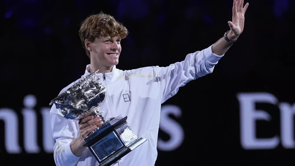 Jannik Sinner of Italy waves as he carries the Norman Brookes Challenge Cup after defeating Alexander Zverev of Germany in the men's singles final at the Australian Open tennis championship in Melbourne, Australia, Sunday, Jan. 26, 2025. (AP Photo/Asanka Brendon Ratnayake)