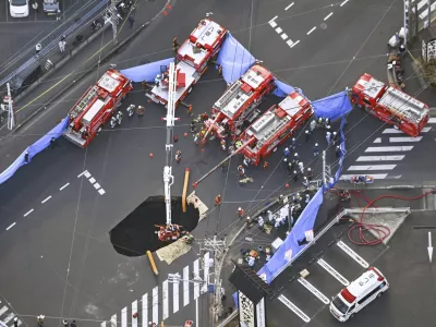 First responders try to rescue the driver of a truck that fell into a sinkhole on a street in Yashio, northeast of Tokyo, Tuesday, Jan. 28, 2025. (Kenichiro Kojima/Kyodo News via AP)