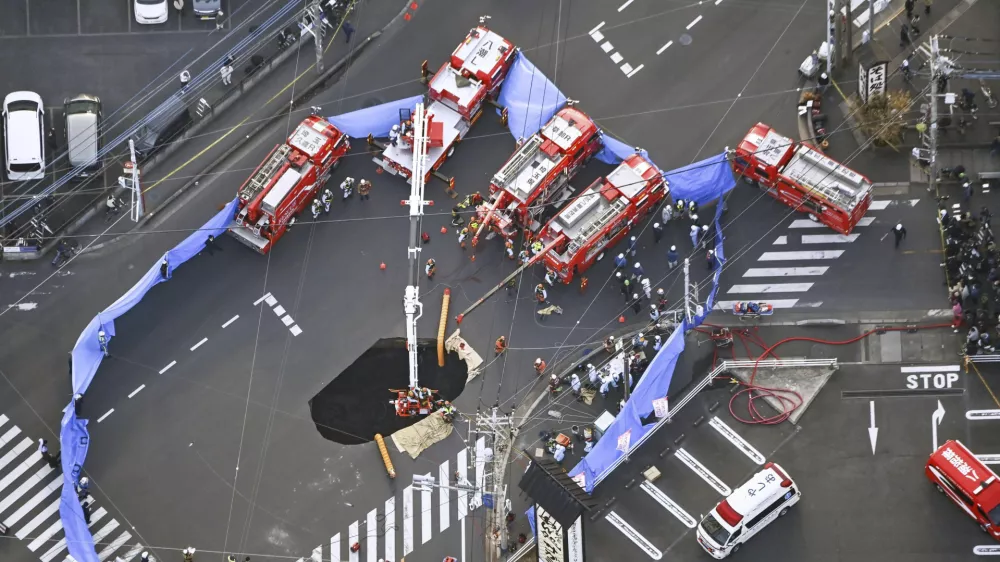 First responders try to rescue the driver of a truck that fell into a sinkhole on a street in Yashio, northeast of Tokyo, Tuesday, Jan. 28, 2025. (Kenichiro Kojima/Kyodo News via AP)