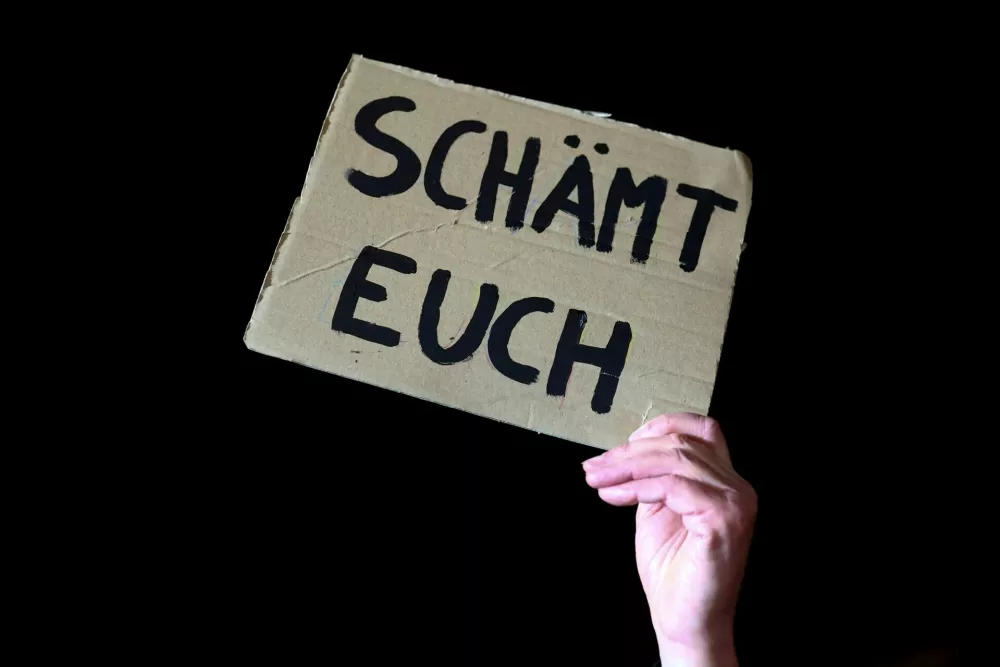 A protester holds a sign reading "Shame on you" in front of the Christian Democratic Union (CDU) party headquarters during a protest after election frontrunner Friedrich Merz succeeded in getting a motion passed in parliament that calls for a migration crackdown including the rejection of asylum seekers at the country's land borders in Berlin, Germany, January 30, 2025. REUTERS/Christian Mang