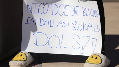 A woman holds a sign outside the American Airlines Center, Sunday, Feb. 2, 2025, in Dallas., Texas. (Elias Valverde II/The Dallas Morning News via AP)