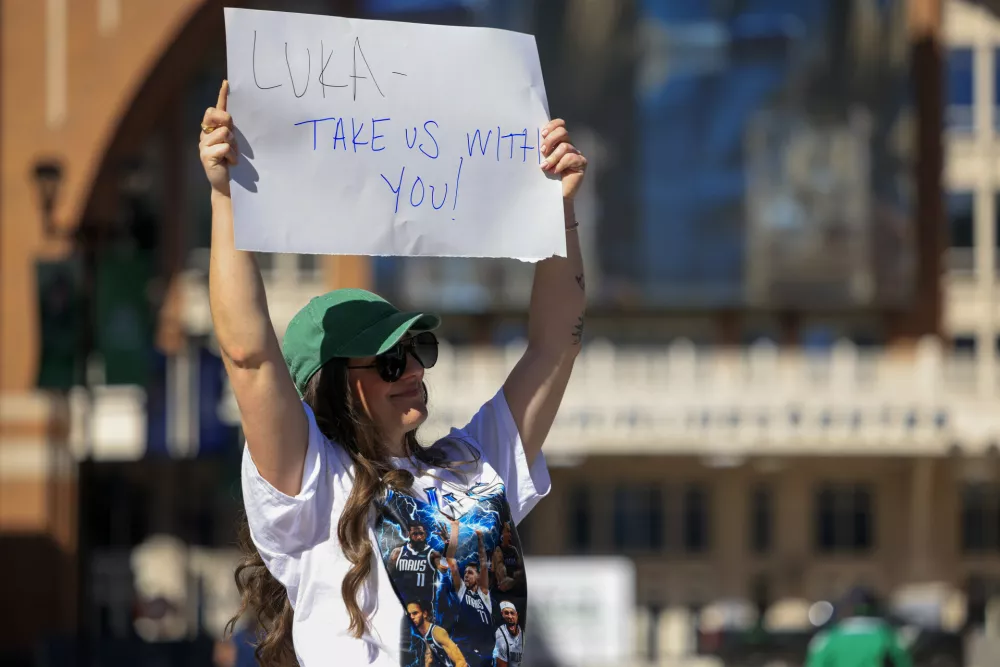 Megan Trosper raises a sign outside the American Airlines Center, Sunday, Feb. 2, 2025, in Dallas., Texas. (Elias Valverde II/The Dallas Morning News via AP)