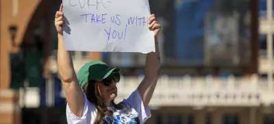 Megan Trosper raises a sign outside the American Airlines Center, Sunday, Feb. 2, 2025, in Dallas., Texas. (Elias Valverde II/The Dallas Morning News via AP)