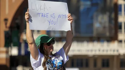 Megan Trosper raises a sign outside the American Airlines Center, Sunday, Feb. 2, 2025, in Dallas., Texas. (Elias Valverde II/The Dallas Morning News via AP)