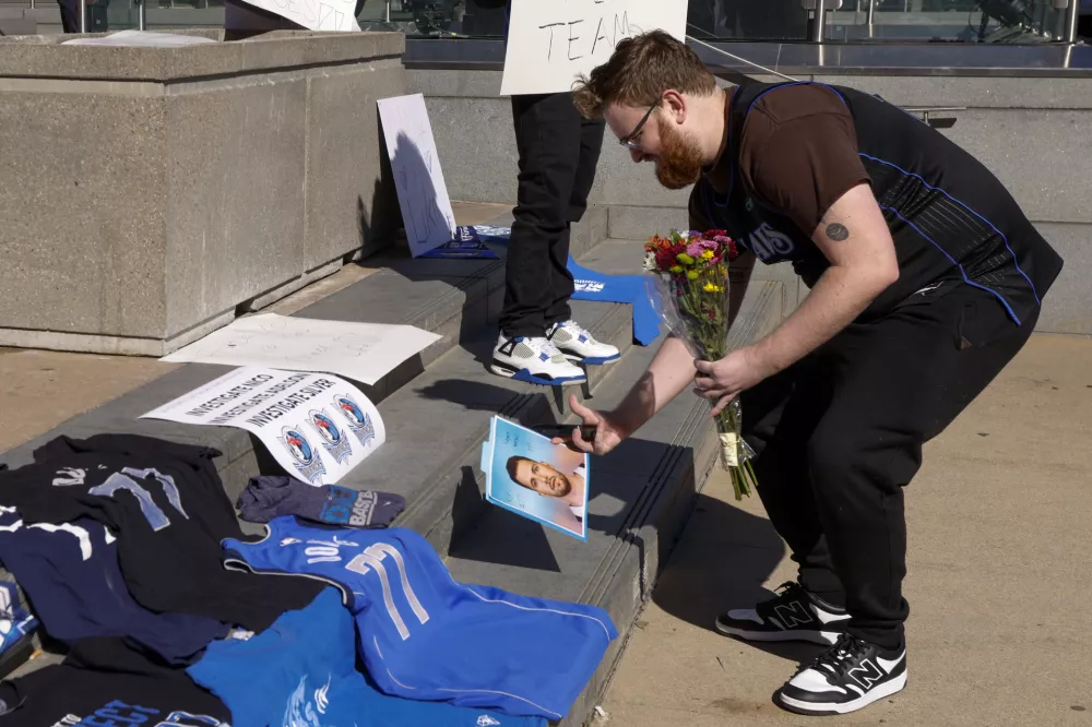 Sam Schlebach of Addison leaves a photo of Luka Doncic and flowers at a tribute to Doncic outside the American Airlines Center after he was traded to the Los Angeles Lakers, Sunday, Feb. 2, 2025, in Dallas. (Elias Valverde II/The Dallas Morning News via AP)