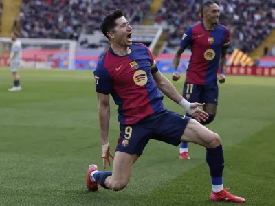 Barcelona's Robert Lewandowski, left, celebrates alongside Raphinha after scoring the opening goal during a Spanish La Liga soccer match between Barcelona and Alaves at the Lluis Companys Olympic Stadium in Barcelona, Spain, Sunday Feb. 2, 2025. (AP Photo/Joan Monfort)