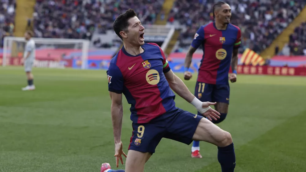 Barcelona's Robert Lewandowski, left, celebrates alongside Raphinha after scoring the opening goal during a Spanish La Liga soccer match between Barcelona and Alaves at the Lluis Companys Olympic Stadium in Barcelona, Spain, Sunday Feb. 2, 2025. (AP Photo/Joan Monfort)