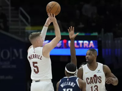 Cleveland Cavaliers guard Sam Merrill (5) looks to shoot next to Dallas Mavericks guard Brandon Williams, center, and Cavaliers' Tristan Thompson (13) in the second half of an NBA basketball game, Sunday, Feb. 2, 2025, in Cleveland. (AP Photo/Sue Ogrocki)