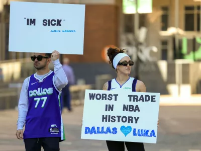 Ryan Safdarinia, left, and Lillian McCall hold signs reacting to the news that the Dallas Mavericks traded Luka Doncic to the Los Angeles Lakers outside the American Airlines Center, Sunday, Feb. 2, 2025, in Dallas. (Elias Valverde II/The Dallas Morning News via AP)