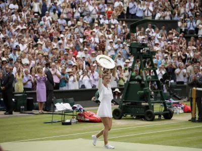 FILE - Romania's Simona Halep holds her trophy after defeating United States' Serena Williams in the women's singles final match on day twelve of the Wimbledon Tennis Championships in London, July 13, 2019. (AP Photo/Tim Ireland, file)