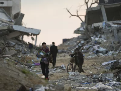 Palestinians walk along a street in Gaza City, littered with rubble from buildings destroyed during the Israeli army's ground and air offensive against Hamas in Gaza City, Tuesday Feb. 4, 2025.(AP Photo/Abdel Kareem Hana)