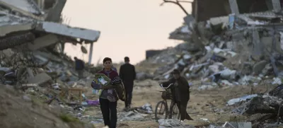 Palestinians walk along a street in Gaza City, littered with rubble from buildings destroyed during the Israeli army's ground and air offensive against Hamas in Gaza City, Tuesday Feb. 4, 2025.(AP Photo/Abdel Kareem Hana)