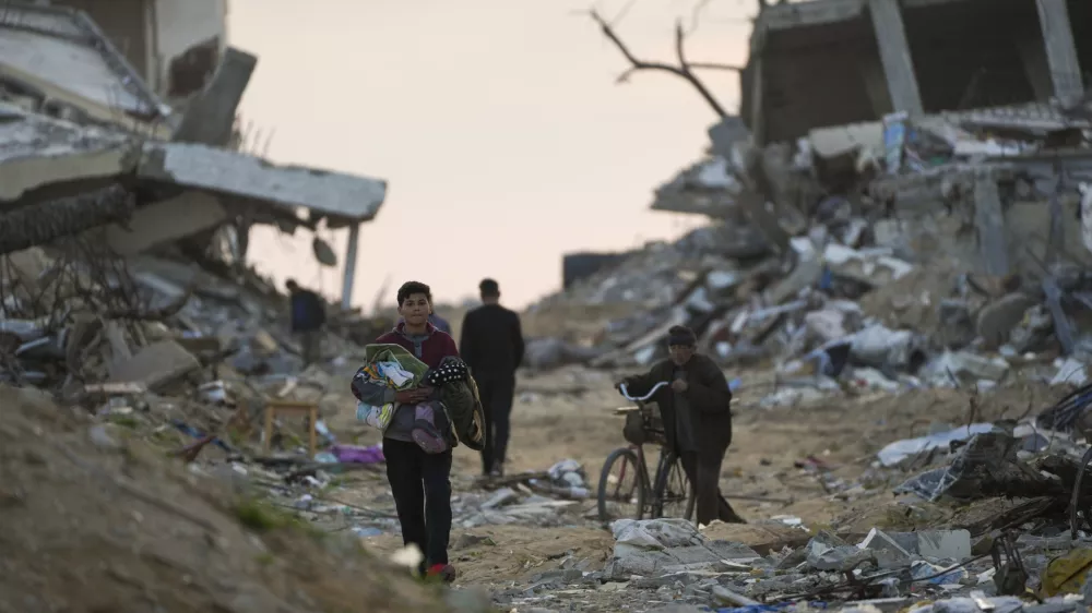 Palestinians walk along a street in Gaza City, littered with rubble from buildings destroyed during the Israeli army's ground and air offensive against Hamas in Gaza City, Tuesday Feb. 4, 2025.(AP Photo/Abdel Kareem Hana)