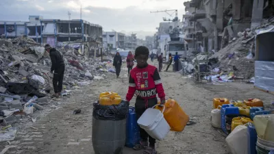 A young Palestinian kid carries jerricans along the destruction caused by the Israeli air and ground offensive in Jabaliya, Gaza Strip, Wednesday, Feb. 5, 2025. (AP Photo/Abdel Kareem Hana)