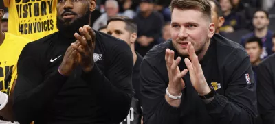 Los Angeles Lakers guard Luka Doncic, right, sits next to forward LeBron James on the bench before an NBA basketball game against the Los Angeles Clippers, Tuesday, Feb. 4, 2025, in Inglewood, Calif. (AP Photo/Kevork Djansezian)