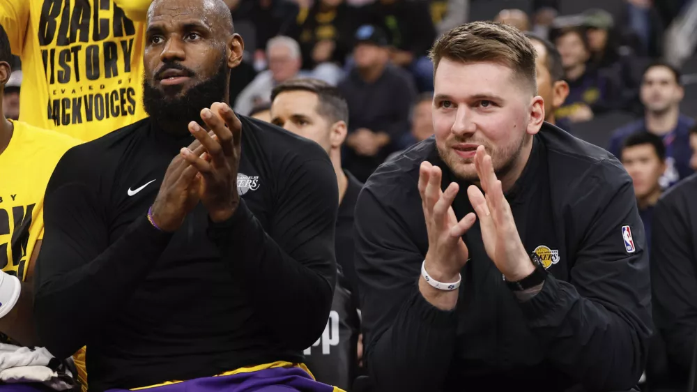 Los Angeles Lakers guard Luka Doncic, right, sits next to forward LeBron James on the bench before an NBA basketball game against the Los Angeles Clippers, Tuesday, Feb. 4, 2025, in Inglewood, Calif. (AP Photo/Kevork Djansezian)