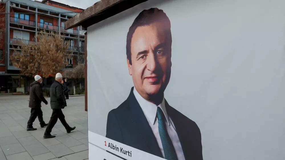 Pedestrians walk near a campaign poster for the upcoming parliamentary elections showing a portrait of Albin Kurti, Kosovo's Prime Minister and leader of the Self-Determination party, in Pristina, Kosovo February 4, 2025. REUTERS/Valdrin Xhemaj