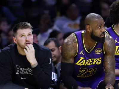 Los Angeles Lakers guard Luka Doncic, left, and forward LeBron James (23) look on from the bench during the first half of an NBA basketball game against the Golden State Warriors, Thursday, Feb. 6, 2025, in Los Angeles. (AP Photo/Kevork Djansezian)