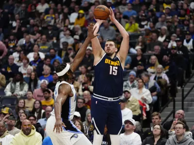 Feb 6, 2025; Denver, Colorado, USA; Denver Nuggets center Nikola Jokic (15) shoots against Orlando Magic forward Paolo Banchero (5) in the second quarter at Ball Arena. Mandatory Credit: Ron Chenoy-Imagn Images