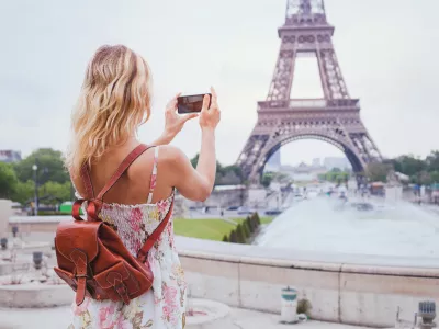 tourist taking photo of Eiffel tower in Paris with compact camera or smartphone, travel in Europe