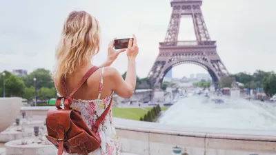 tourist taking photo of Eiffel tower in Paris with compact camera or smartphone, travel in Europe