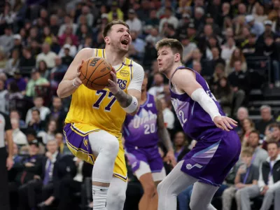 Feb 12, 2025; Salt Lake City, Utah, USA; Los Angeles Lakers guard Luka Doncic (77) is fouled by Utah Jazz forward Kyle Filipowski (22) during the second quarter at Delta Center. Mandatory Credit: Chris Nicoll-Imagn Images