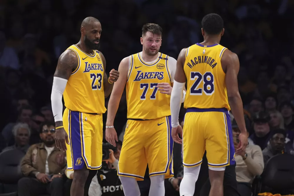 Los Angeles Lakers guard Luka Doncic (77) confers with teammates forward LeBron James, left, and forward Rui Hachimura during the second half of an NBA basketball game against the Utah Jazz, Monday, Feb. 10, 2025, in Los Angeles. (AP Photo/Mark J. Terrill)