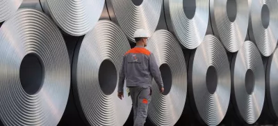 FILED - 12 July 2020, Lower Saxony, Salzgitter: An employee walks along coiled steel at Salzgitter AG. US President Donald Trump's announcement that he is planning to impose 25% tariffs on steel and aluminium imports is hitting the EU steel sector at the worst possible time, a German industry association said on Monday. Photo: Julian Stratenschulte/dpa