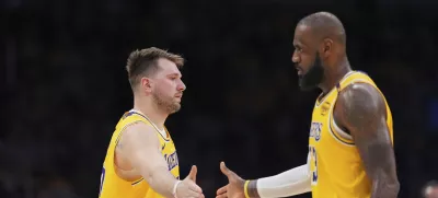 Los Angeles Lakers guard Luka Doncic, left, touches hands with teammate forward LeBron James during the first half of an NBA basketball game against the Utah Jazz, Monday, Feb. 10, 2025, in Los Angeles. (AP Photo/Mark J. Terrill)