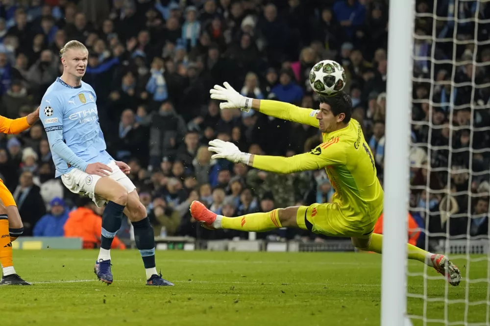 Manchester City's Erling Haaland shoots to score past Real Madrid's goalkeeper Thibaut Courtois, right, during the Champions League playoff first leg soccer match between Manchester City and Real Madrid at the Etihad Stadium in Manchester, England, Tuesday, Feb. 11, 2025. (AP Photo/Dave Thompson)