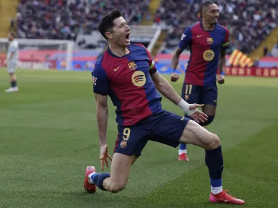 Barcelona's Robert Lewandowski, left, celebrates alongside Raphinha after scoring the opening goal during a Spanish La Liga soccer match between Barcelona and Alaves at the Lluis Companys Olympic Stadium in Barcelona, Spain, Sunday Feb. 2, 2025. (AP Photo/Joan Monfort)