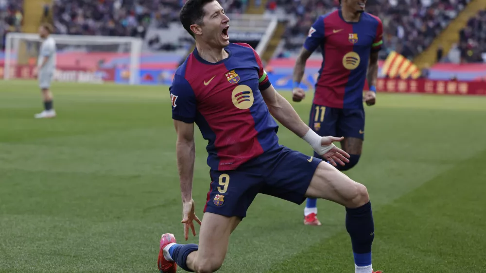 Barcelona's Robert Lewandowski, left, celebrates alongside Raphinha after scoring the opening goal during a Spanish La Liga soccer match between Barcelona and Alaves at the Lluis Companys Olympic Stadium in Barcelona, Spain, Sunday Feb. 2, 2025. (AP Photo/Joan Monfort)