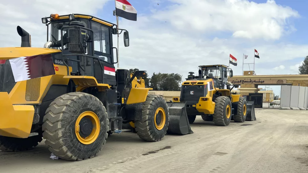 Bulldozers with Egyptian and Qatar flags wait to enter Gaza at the Rafah border crossing between Egypt and the Gaza Strip, Thursday, Feb. 13, 2025. (AP Photo/Mohamed Arafat)