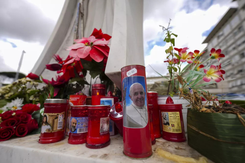 Candles, one showing a photo of Pope Francis, are seen in front of the Agostino Gemelli Polyclinic in Rome, Friday, Feb. 14, 2025, where Pope Francis has been hospitalized to undergo some necessary diagnostic tests and to continue his ongoing treatment for bronchitis. (AP Photo/Andrew Medichini)