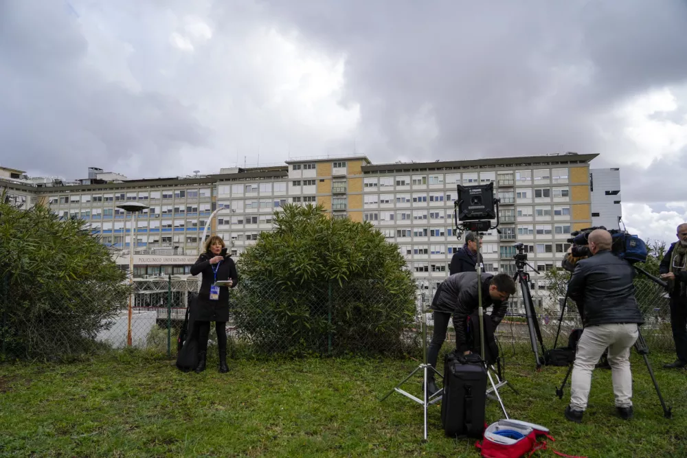 Members of the media take position outside the Agostino Gemelli Polyclinic in Rome, Friday, Feb. 14, 2025, where Pope Francis has been hospitalized to undergo some necessary diagnostic tests and to continue his ongoing treatment for bronchitis. (AP Photo/Gregorio Borgia)