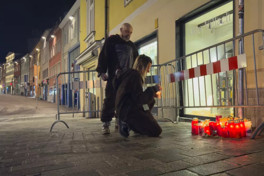 A person lights a candle at the site of a stabbing attack in Villach, Austria, Sunday, Feb. 16, 2025. (AP Photo/Darko Bandic)