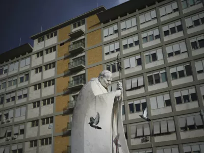 A marble statue of late Pope John Paul II is backdropped by the Agostino Gemelli Polyclinic in Rome, Saturday, Feb. 15, 2025, where Pope Francis was hospitalised Friday after a weeklong bout of bronchitis worsened and is receiving drug therapy for a respiratory tract infection. (AP Photo/Alessandra Tarantino)