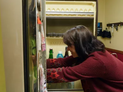 An adult latin woman is looking food into a refrigerator and smiling. She is wearing a red sweater and has a bottle of beer in her hand, lifestyles concept, copy space.,Image: 878079177, License: Royalty-free, Restrictions:, Model Release: yesFoto: Profimedia