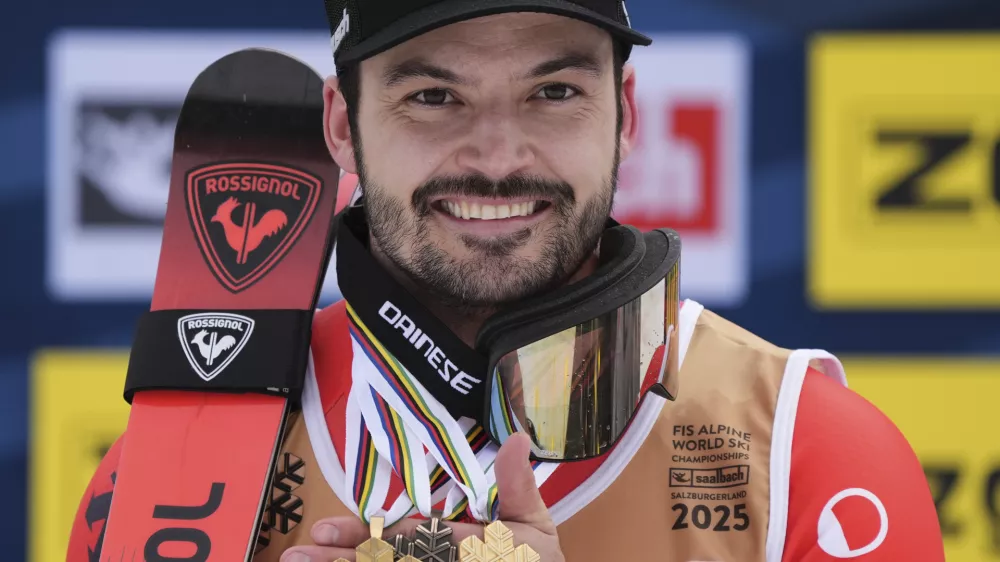 Switzerland's Loic Meillard shows his gold medals for a men's slalom and for team combined event, left, and right, and a bronze medal for a giant slalom center, at the Alpine Ski World Championships, in Saalbach-Hinterglemm, Austria, Sunday, Feb. 16, 2025. (AP Photo/Giovanni Auletta)