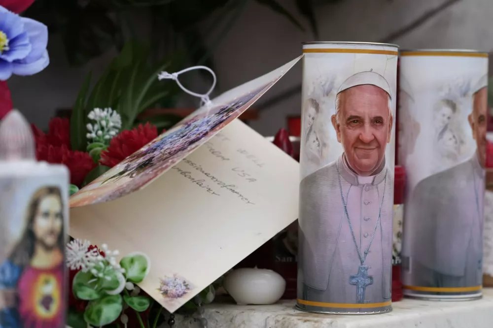 Candles with the pictures of Pope Francis are the laid under the statue of late Pope John Paul II outside Agostino Gemelli Polyclinic in Rome, Wednesday, Feb. 19, 2025, where the Pontiff is hospitalized since Friday, Feb. 14. (AP Photo/Gregorio Borgia)