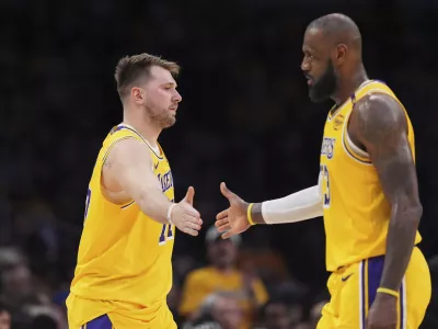 Los Angeles Lakers guard Luka Doncic, left, touches hands with teammate forward LeBron James during the first half of an NBA basketball game against the Utah Jazz, Monday, Feb. 10, 2025, in Los Angeles. (AP Photo/Mark J. Terrill)