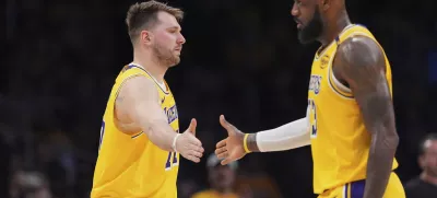 Los Angeles Lakers guard Luka Doncic, left, touches hands with teammate forward LeBron James during the first half of an NBA basketball game against the Utah Jazz, Monday, Feb. 10, 2025, in Los Angeles. (AP Photo/Mark J. Terrill)