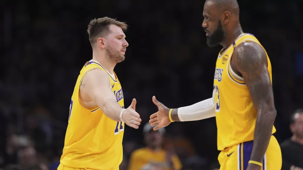 Los Angeles Lakers guard Luka Doncic, left, touches hands with teammate forward LeBron James during the first half of an NBA basketball game against the Utah Jazz, Monday, Feb. 10, 2025, in Los Angeles. (AP Photo/Mark J. Terrill)