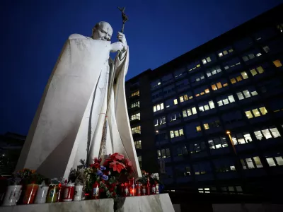 A statue of the late Pope John Paul II stands surrounded by candles and flowers outside the Gemelli Hospital where Pope Francis has gone to continue treatment for ongoing bronchitis, in Rome, Italy, February 17, 2025. REUTERS/Guglielmo Mangiapane   TPX IMAGES OF THE DAY